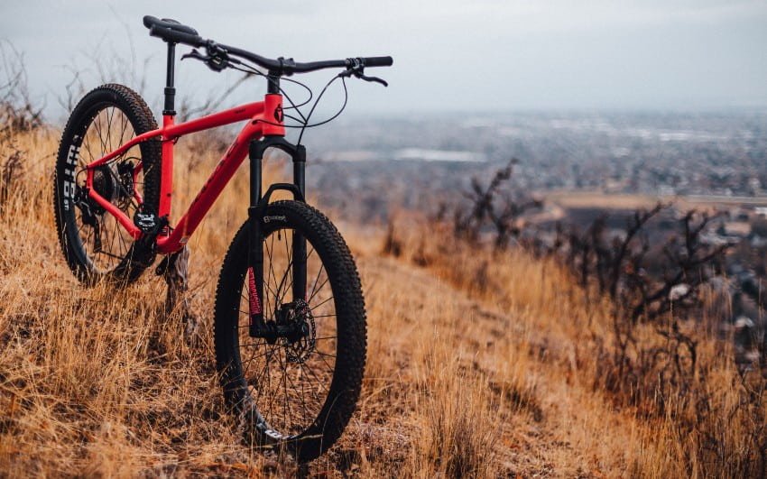 red hardtail mountain bike on a grass hill.
